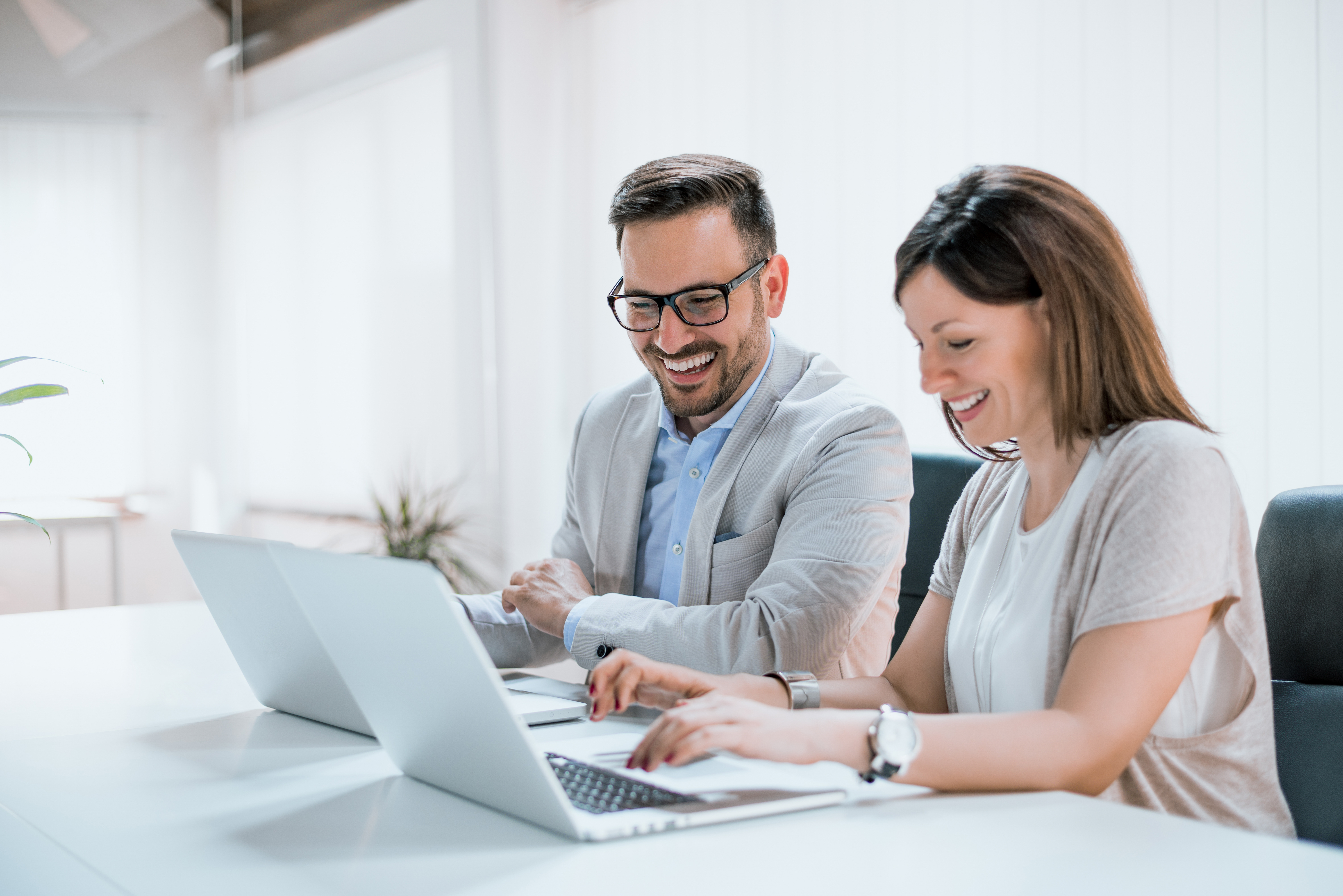 Mann und Frau sitzen an ihren Laptops