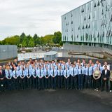 Neue Polizistinnen und Polizisten stehen mit der Abteilungsleitung auf dem Vorplatz vor der Wache Mettmann zu einem Gruppenfoto zusammen.